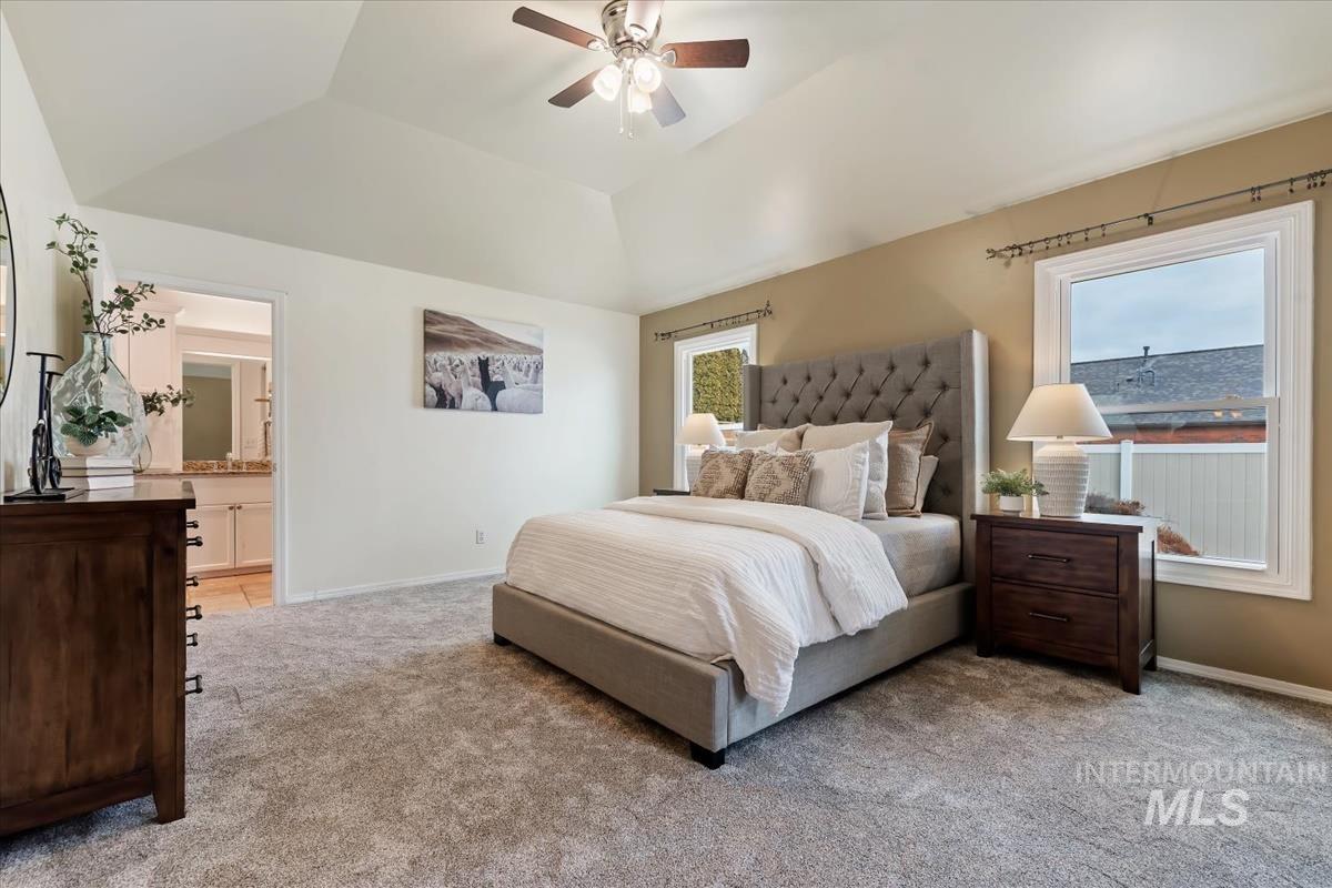 7790 Ustick Road Nampa, ID 83687 - Photo 16 of 41 Bedroom with light carpet, ceiling fan, multiple windows, vaulted ceiling, and ensuite bath