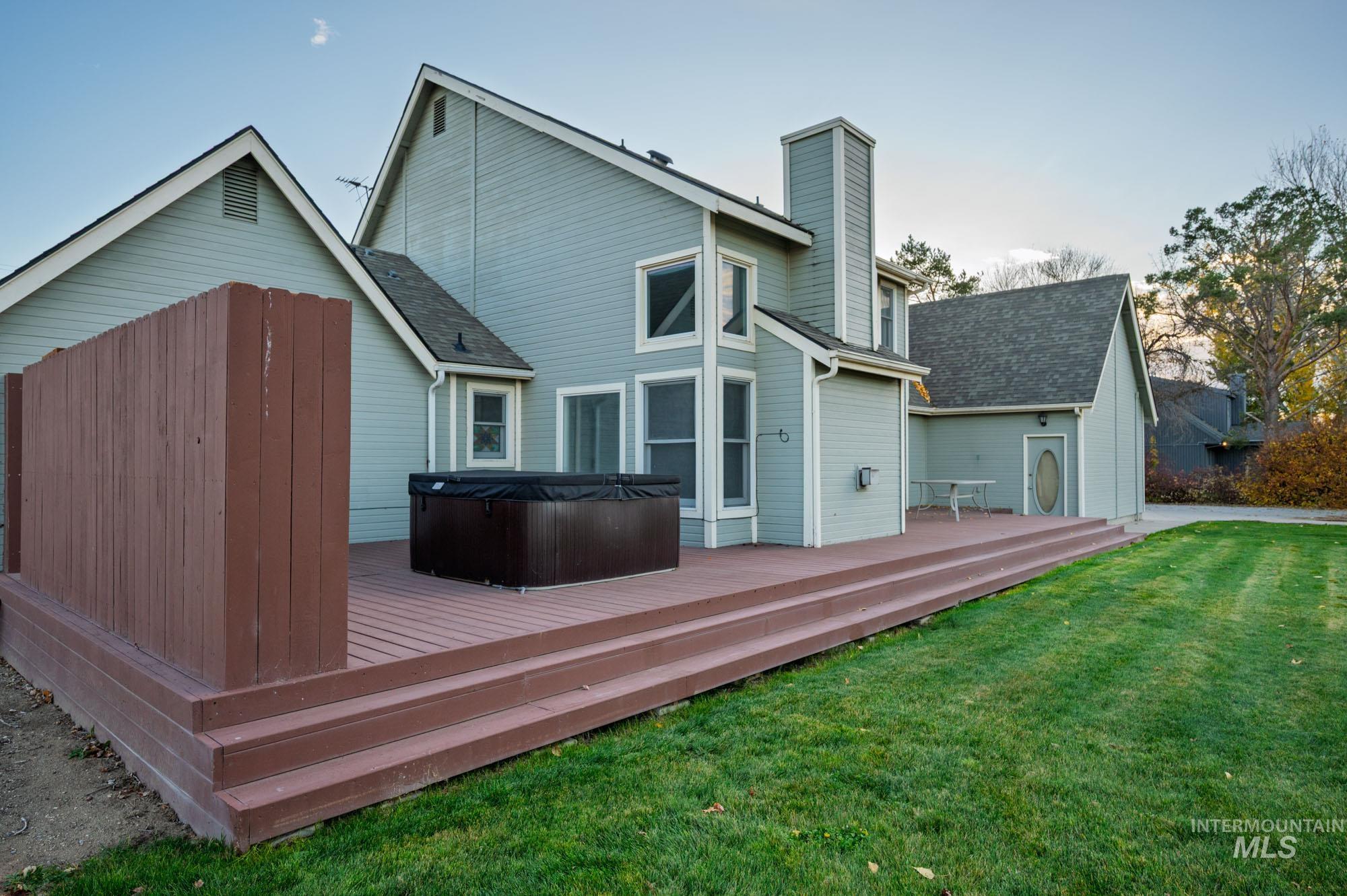 7790 Ustick Road Nampa, ID 83687 - Photo 25 of 41 Back of house featuring a lawn, a hot tub, a wooden deck, roof with shingles, and a chimney