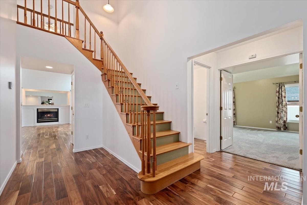 7790 Ustick Road Nampa, ID 83687 - Photo 4 of 41 Staircase with hardwood / wood-style floors, a high ceiling, and a warm lit fireplace