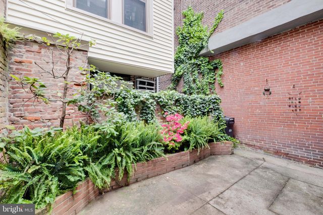 a flower plants and a bench in front of a house