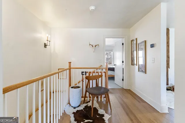 a view of a hallway with wooden floor and a bathroom