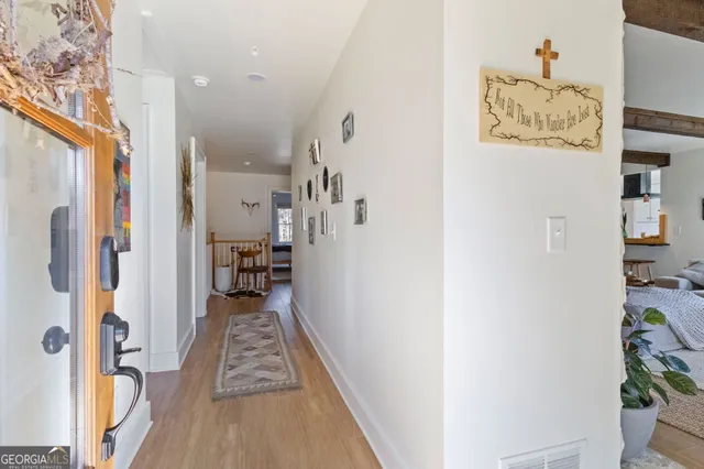 a view of a hallway with wooden floor and a bathroom