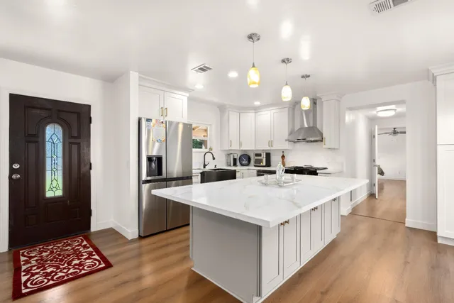 a large kitchen with kitchen island wooden floor center island and stainless steel appliances