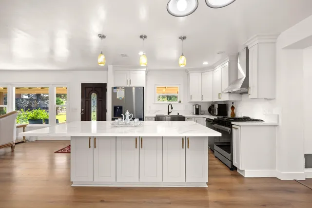 a large white kitchen with lots of counter space a sink and appliances