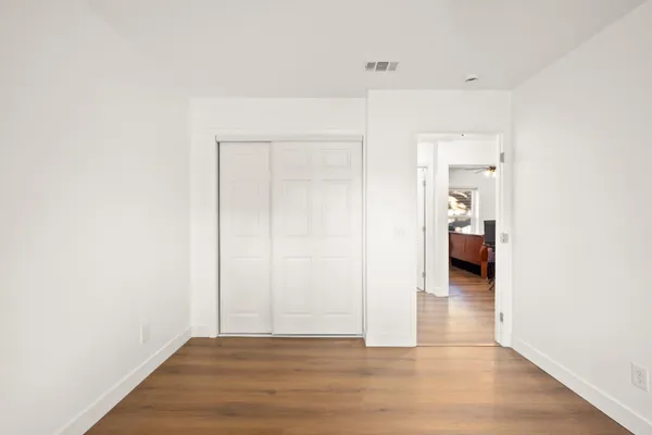 a view of a hallway with wooden floor and a bathroom