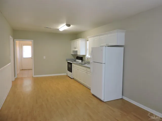 a view of a kitchen with a sink refrigerator and wooden floor