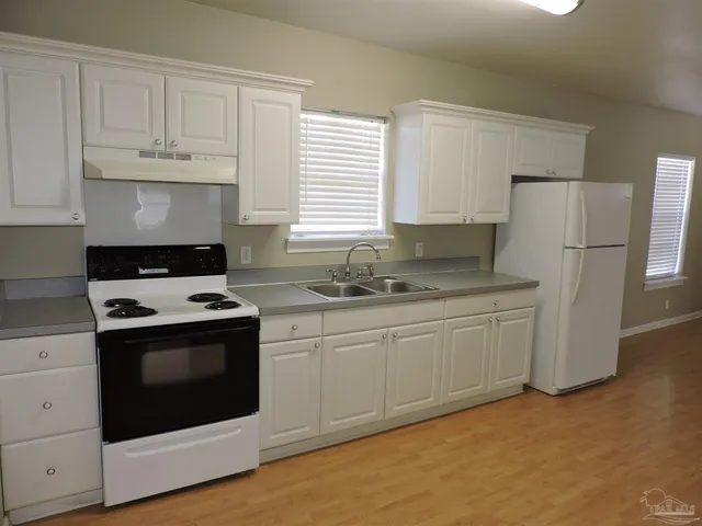 a kitchen with granite countertop white cabinets and white stove