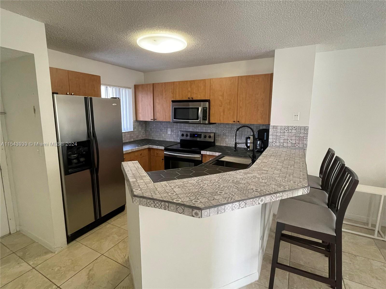 a kitchen with stainless steel appliances granite countertop a refrigerator a stove a sink a washer and dryer