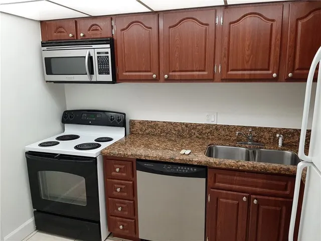 a kitchen with granite countertop a stove top oven microwave and cabinets