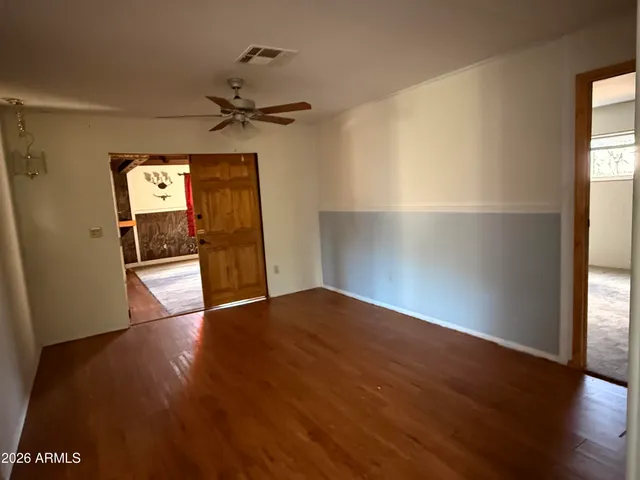 an empty room with wooden floor cabinet and windows
