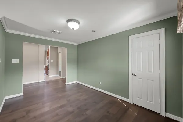 a view of an empty room with wooden floor and closet