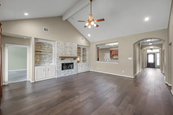 a view of an empty room with wooden floor fireplace and a window