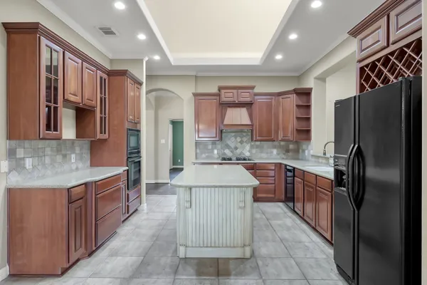 a large kitchen with stainless steel appliances kitchen island granite countertop a refrigerator and a stove top oven