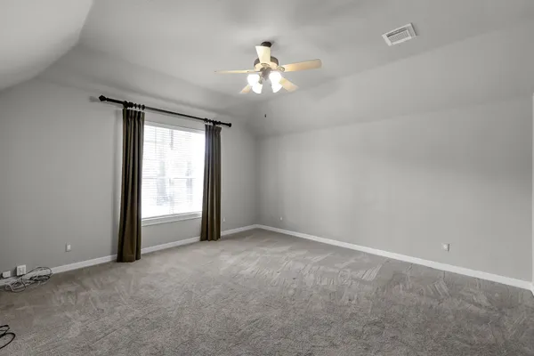 an empty room with a chandelier fan and windows