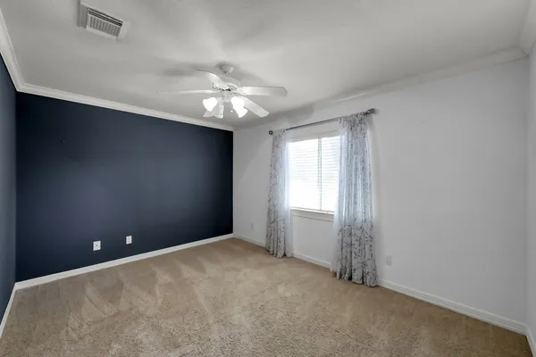 an empty room with a chandelier fan and windows