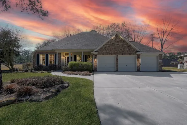 a front view of a house with a garden and trees
