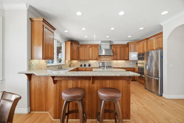 a kitchen with stainless steel appliances granite countertop a sink a stove and a refrigerator