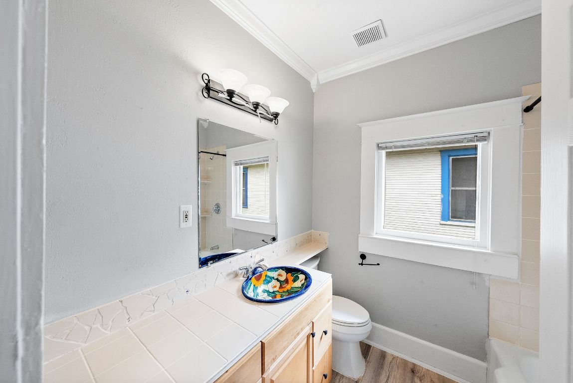 2032 East Cesar Chavez Street Austin, TX 78702 - Photo 15 of 25 Bathroom featuring crown molding, toilet, wood finished floors, vanity, and baseboards