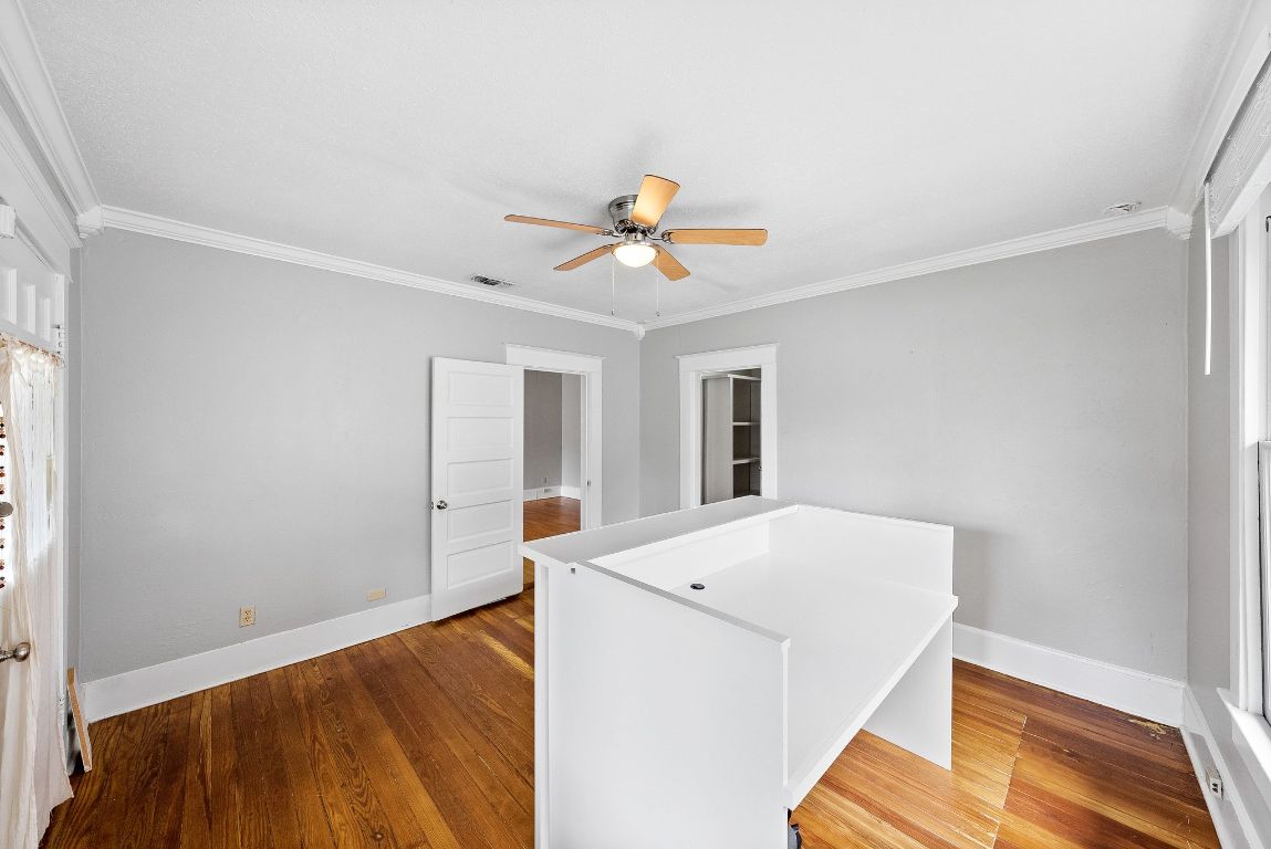 2032 East Cesar Chavez Street Austin, TX 78702 - Photo 3 of 25 Spare room featuring crown molding, hardwood / wood-style flooring, a ceiling fan, and baseboards