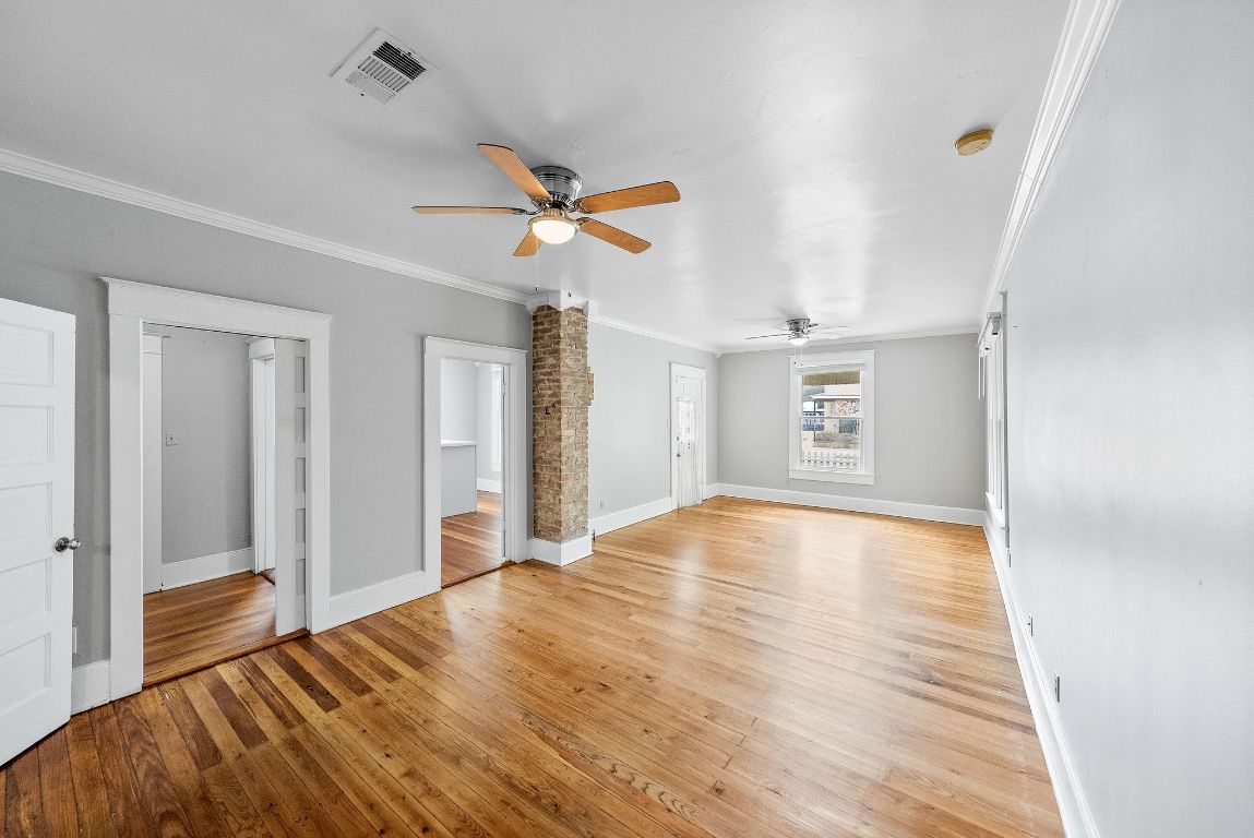 2032 East Cesar Chavez Street Austin, TX 78702 - Photo 5 of 25 Unfurnished living room featuring a ceiling fan, ornamental molding, baseboards, and light wood finished floors