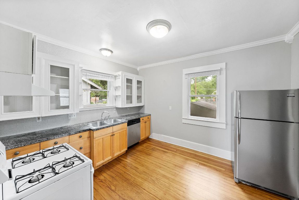 2032 East Cesar Chavez Street Austin, TX 78702 - Photo 7 of 25 Kitchen featuring stainless steel appliances, a sink, crown molding, light wood-type flooring, and baseboards
