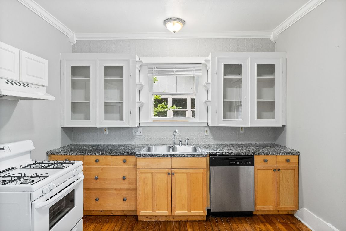 2032 East Cesar Chavez Street Austin, TX 78702 - Photo 8 of 25 Kitchen with dishwasher, white range with gas stovetop, a sink, under cabinet range hood, and dark wood-style floors