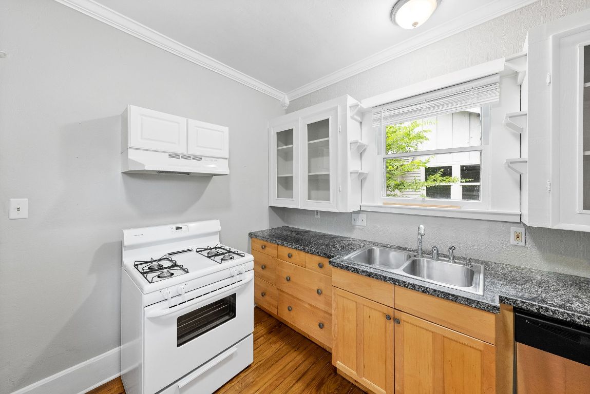2032 East Cesar Chavez Street Austin, TX 78702 - Photo 9 of 25 Kitchen featuring white gas stove, a sink, stainless steel dishwasher, under cabinet range hood, and ornamental molding