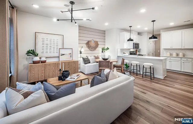 a living room with furniture kitchen view and a wooden floor