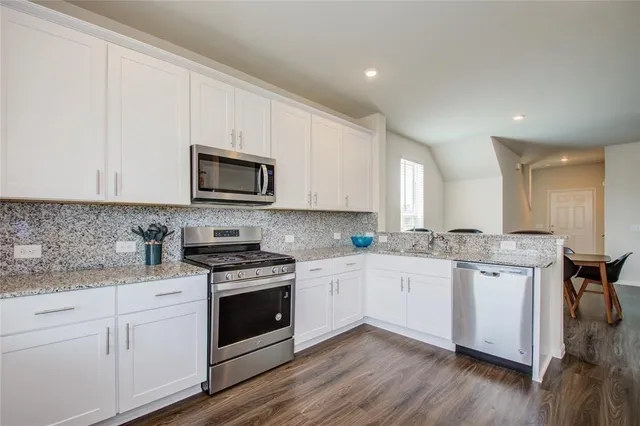 a kitchen with granite countertop white cabinets and white appliances