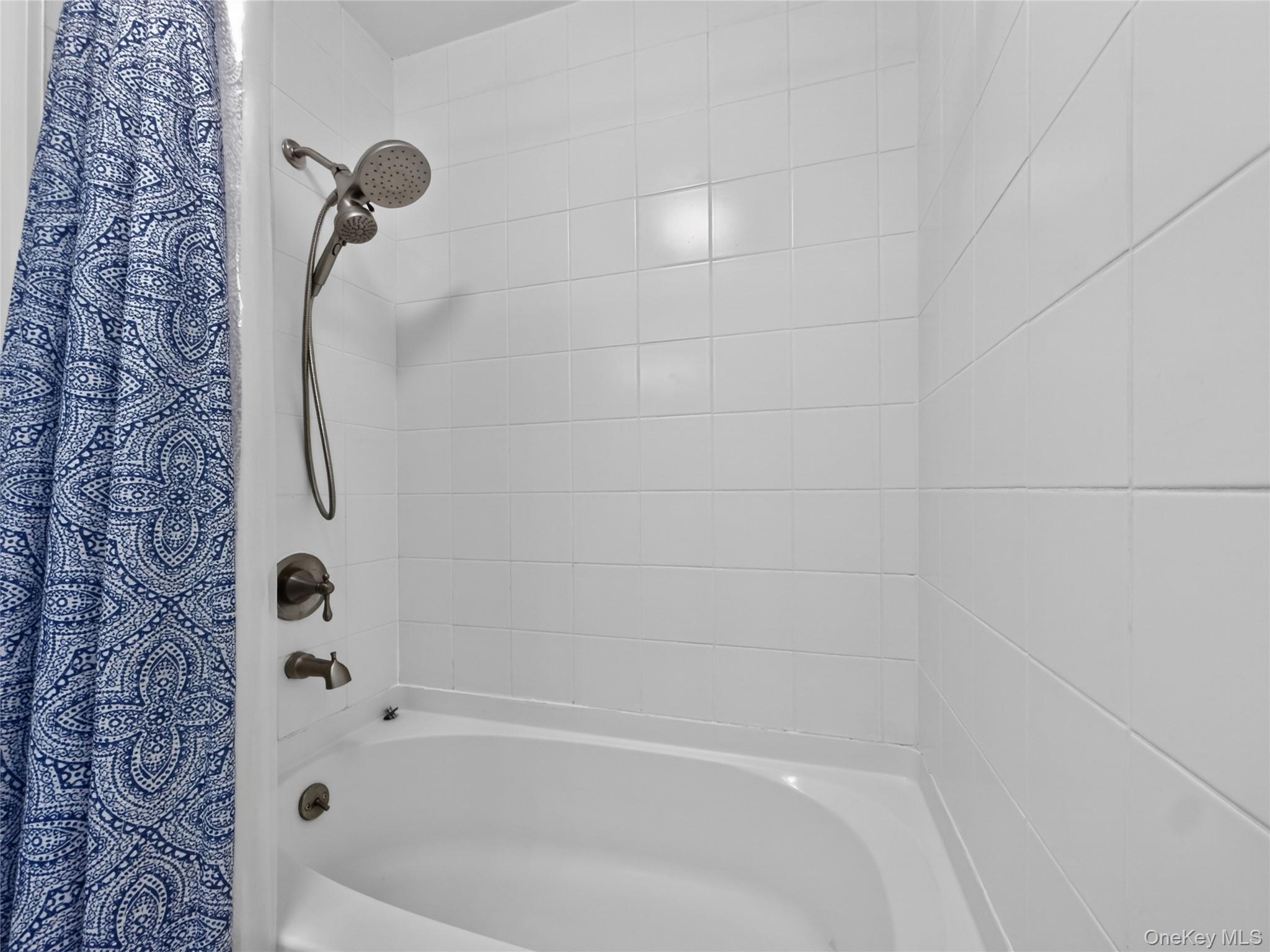 26 Cooper Road, Unit 414 Poughkeepsie, NY 12603 - Photo 22 of 24 White ceramic subway tile surround with a tub/shower combination