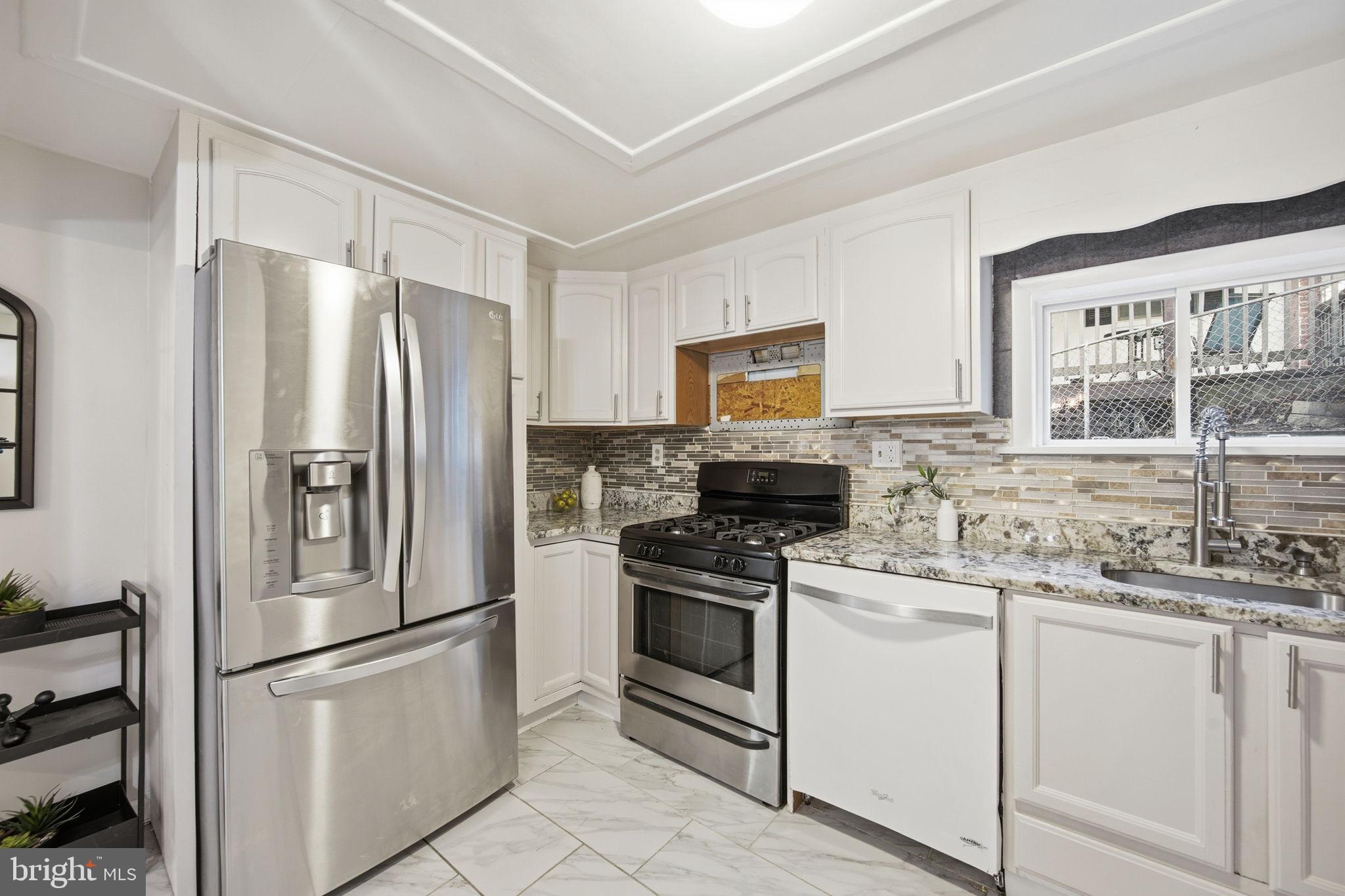 a kitchen with white cabinets stainless steel appliances and window