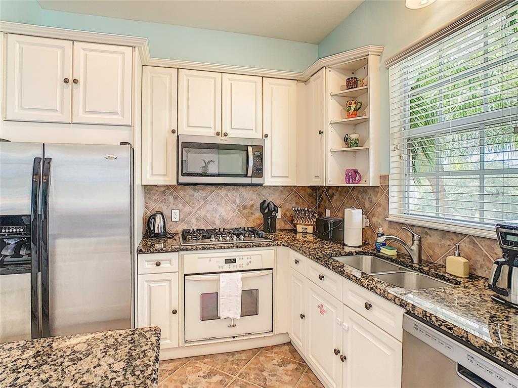 1424 Titian Court Reunion, FL 34747 - Photo 15 of 63 a kitchen with stainless steel appliances granite countertop a stove a sink and a refrigerator