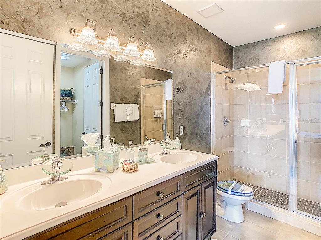 1424 Titian Court Reunion, FL 34747 - Photo 28 of 63 a bathroom with a double vanity sink toilet mirror and shower