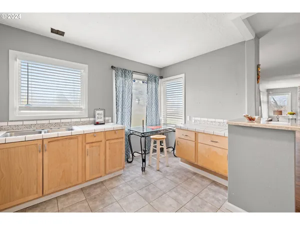 a large white kitchen with granite countertop a sink white cabinets and a large window
