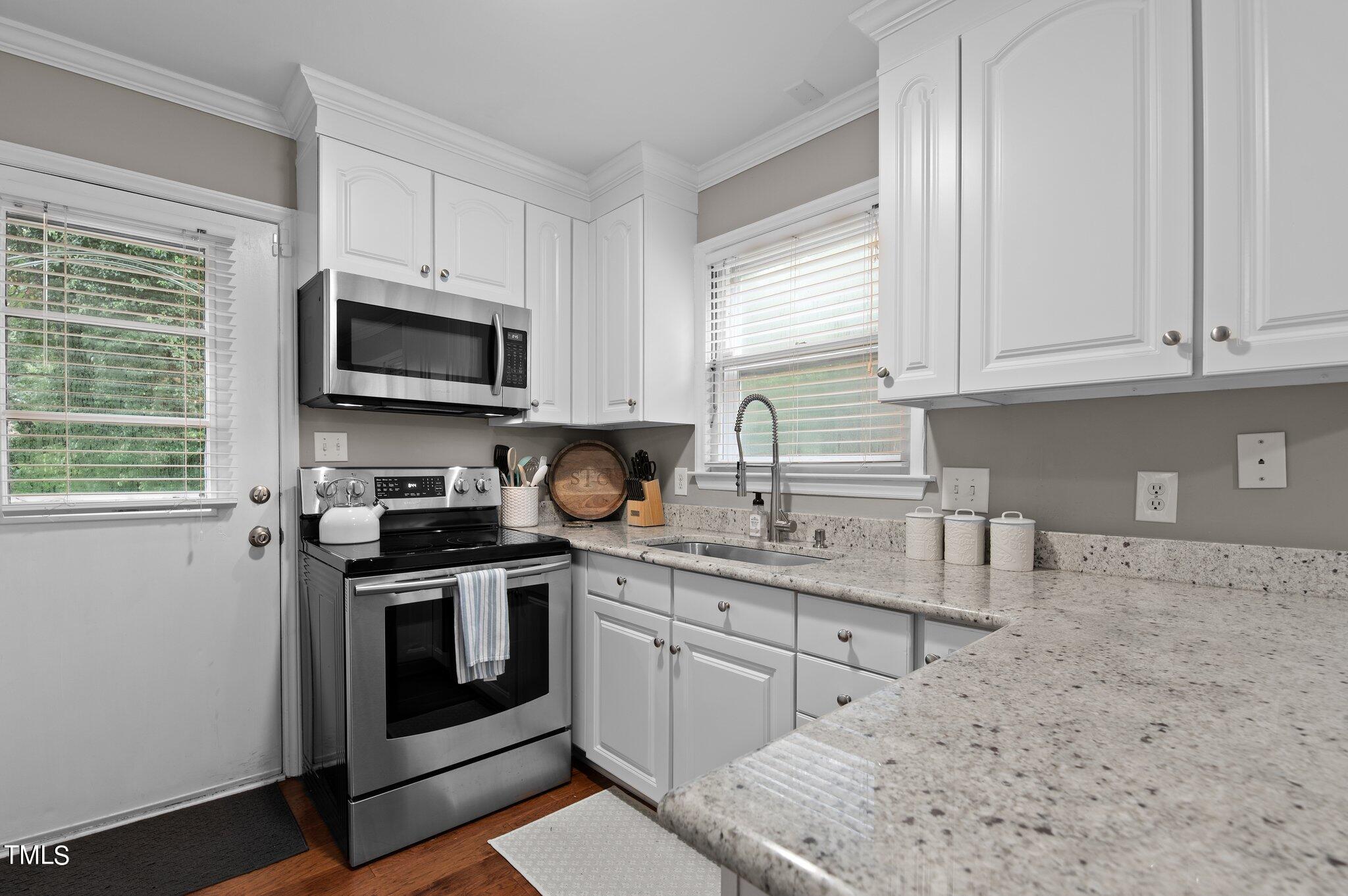 801 Purdue Street Raleigh, NC 27609 - Photo 12 of 40 a kitchen with stainless steel appliances granite countertop a sink a stove a microwave and wooden cabinets