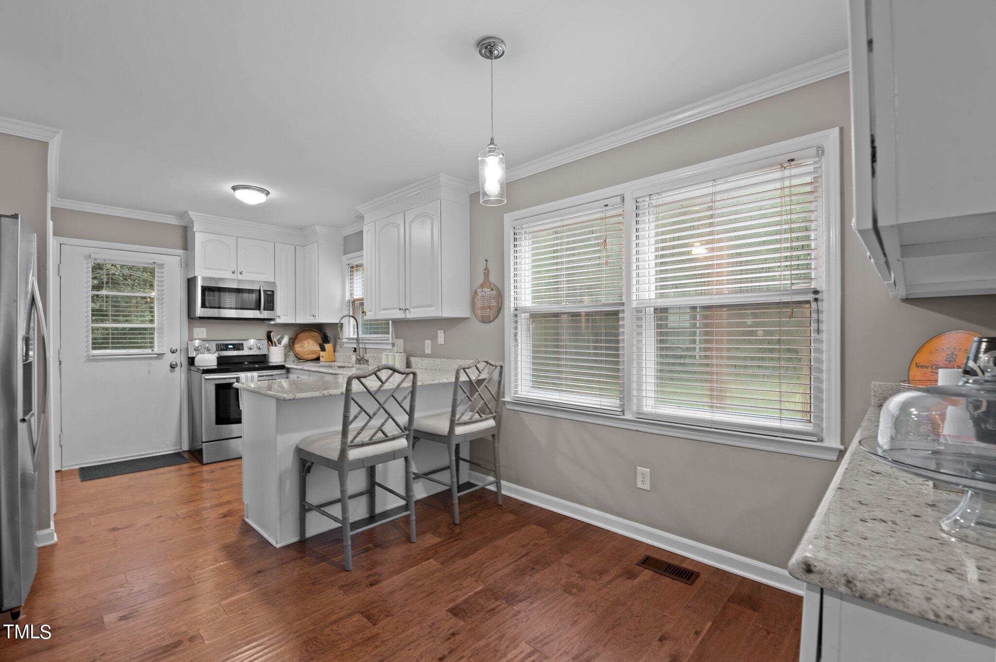 801 Purdue Street Raleigh, NC 27609 - Photo 15 of 40 a kitchen with stainless steel appliances granite countertop a stove top oven a sink dishwasher a dining table and chairs with wooden floor