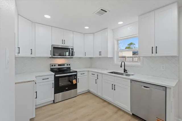 a kitchen with white cabinets and appliances
