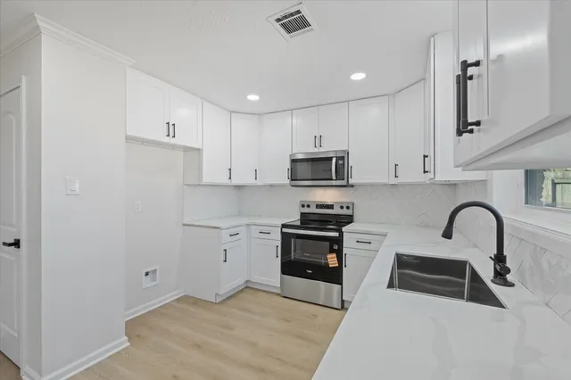 a kitchen with white cabinets stainless steel appliances and sink