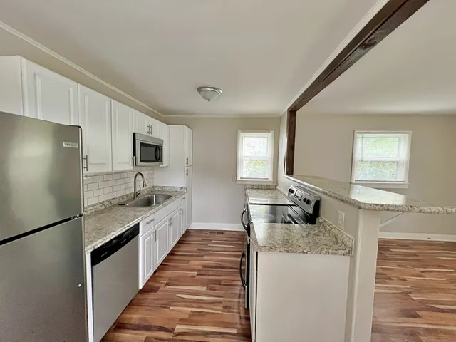 a large kitchen with granite countertop a sink and refrigerator