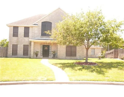 a view of a brick house with a big yard and large trees