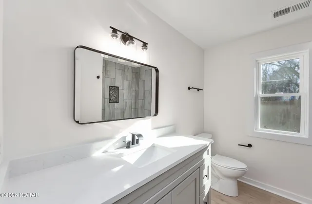 a bathroom with a toilet a sink a vanity and mirror