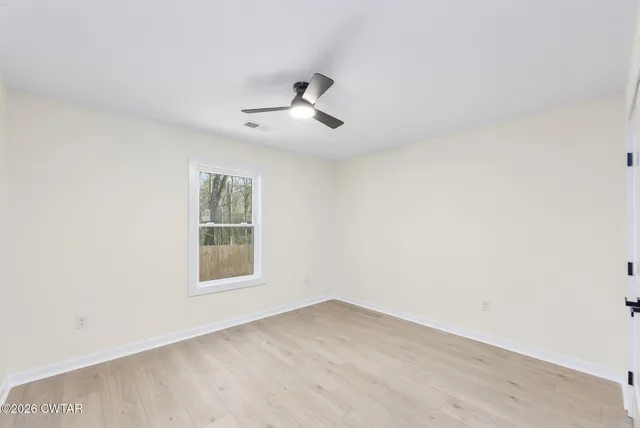 an empty room with a window and ceiling fan