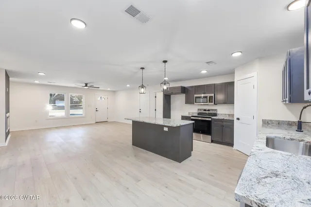 a large kitchen with kitchen island a large counter top space a sink stainless steel appliances and cabinets