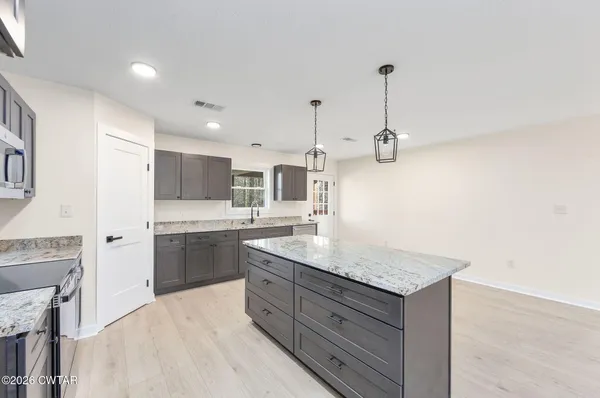 a kitchen with kitchen island a sink stainless steel appliances and cabinets