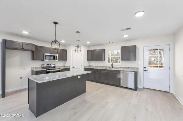 a kitchen with stainless steel appliances kitchen island granite countertop a stove a sink and a refrigerator
