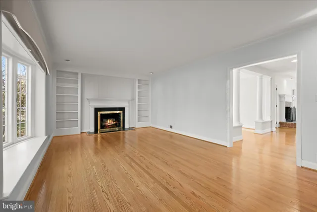 a view of an empty room with a window and wooden floor