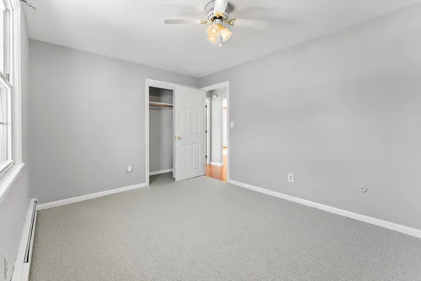 an empty room with a chandelier fan and windows