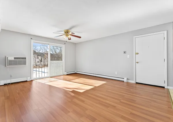 a view of an empty room with wooden floor and a window