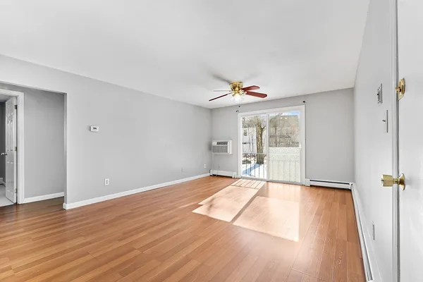 a view of an empty room with wooden floor and a window