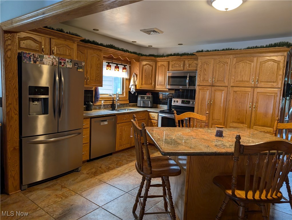 46136 Carlisle Road Lisbon, OH 44432 - Photo 35 of 48 Kitchen with tasteful backsplash, a center island, sink, a breakfast bar, and appliances with stainless steel finishes
